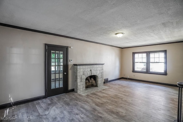 unfurnished living room with a textured ceiling, wood-type flooring, ornamental molding, and a tile fireplace