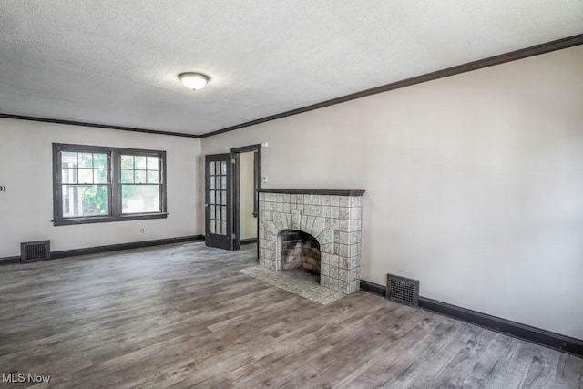 unfurnished living room featuring a textured ceiling, crown molding, a tiled fireplace, and hardwood / wood-style flooring