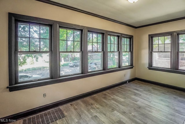 unfurnished room with ornamental molding, hardwood / wood-style floors, and a healthy amount of sunlight