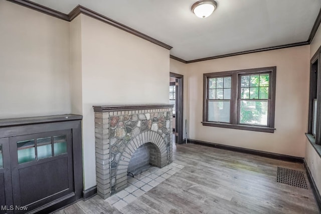 unfurnished living room featuring light hardwood / wood-style flooring, a fireplace, and ornamental molding