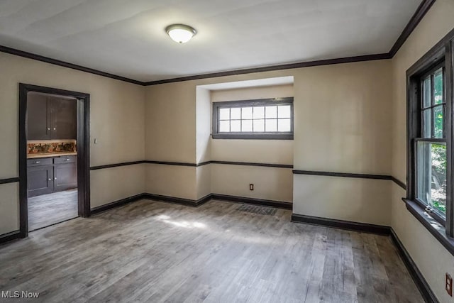 unfurnished room with a healthy amount of sunlight, ornamental molding, and light hardwood / wood-style flooring