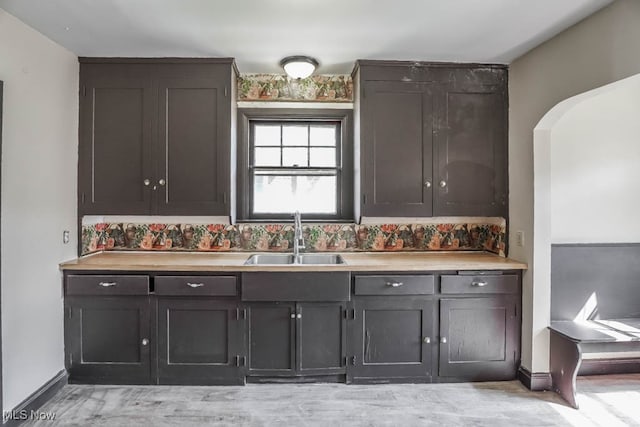 kitchen featuring backsplash, dark brown cabinetry, and sink