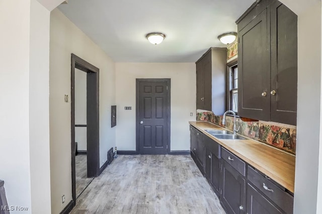 interior space featuring dark brown cabinets, light wood-type flooring, and sink