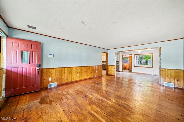 interior space with crown molding, wood walls, hardwood / wood-style floors, and a textured ceiling