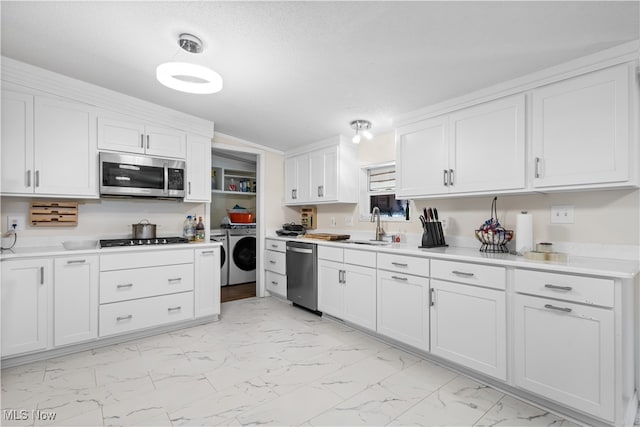 kitchen featuring white cabinets, sink, appliances with stainless steel finishes, and washer and dryer