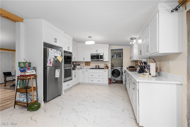 kitchen featuring washing machine and dryer, white cabinetry, and stainless steel appliances