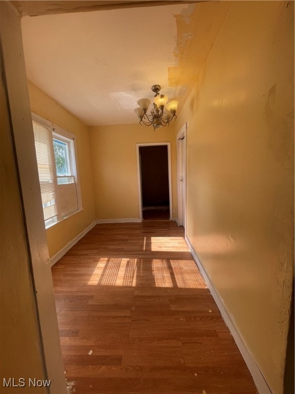 corridor featuring hardwood / wood-style floors and a notable chandelier