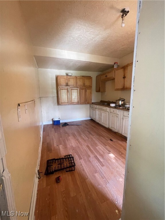 kitchen featuring a textured ceiling, light brown cabinetry, and light hardwood / wood-style flooring