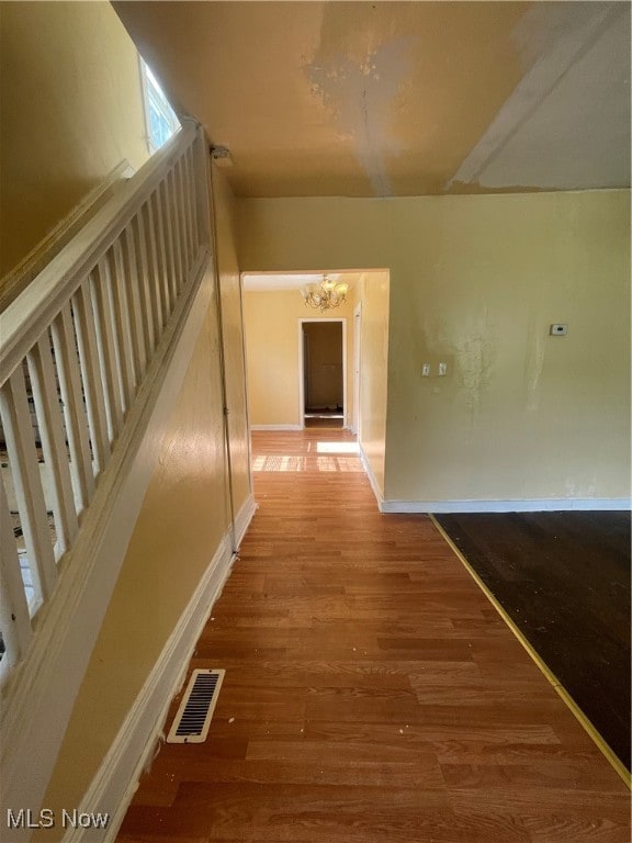 corridor with an inviting chandelier and hardwood / wood-style floors