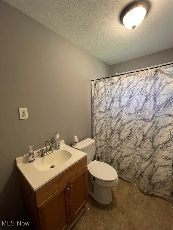 bathroom with vanity, a textured ceiling, and toilet