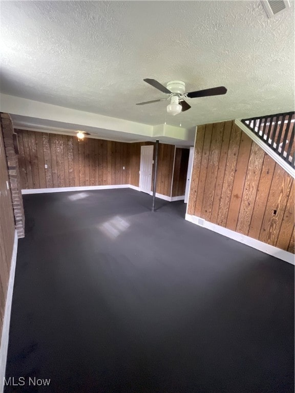 spare room with wooden walls, a textured ceiling, and ceiling fan