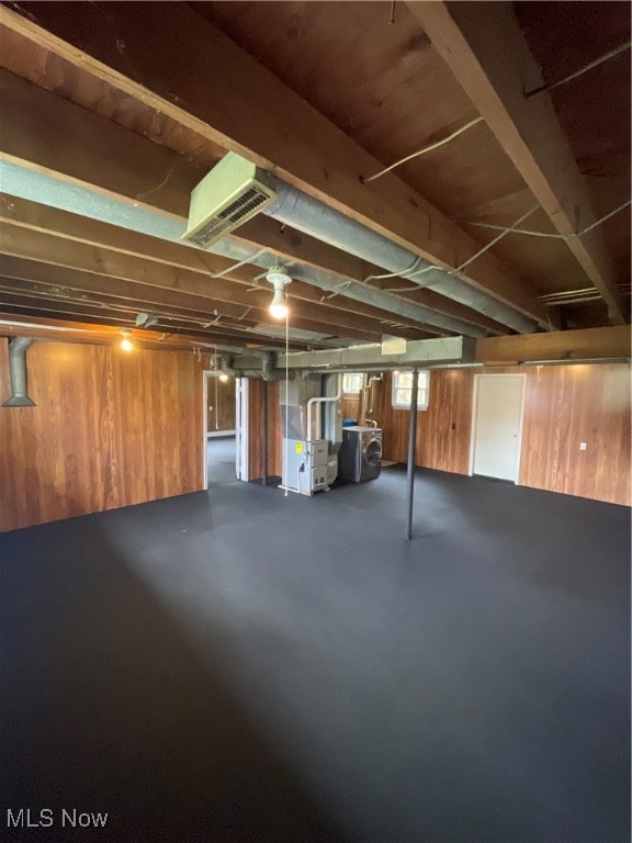 basement featuring washer / dryer, heating unit, and wooden walls