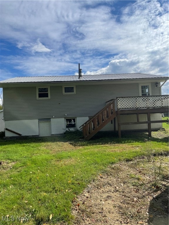 back of property featuring a wooden deck and a yard