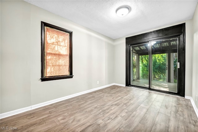 spare room with light wood-type flooring and a textured ceiling