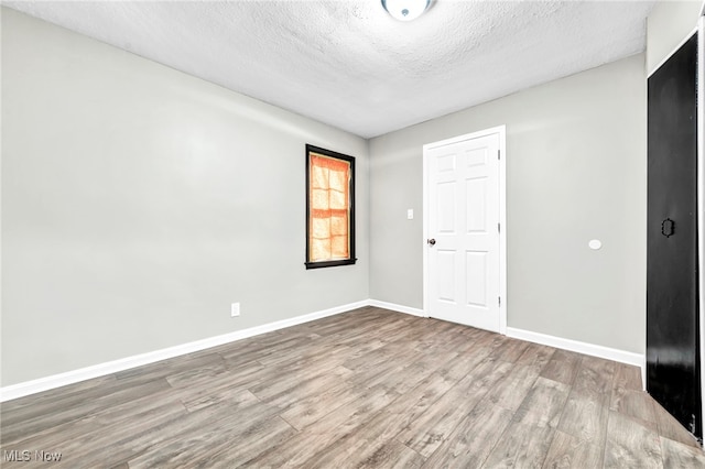 spare room featuring hardwood / wood-style floors and a textured ceiling