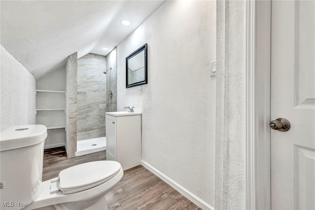 bathroom with toilet, tiled shower, wood-type flooring, a textured ceiling, and vaulted ceiling