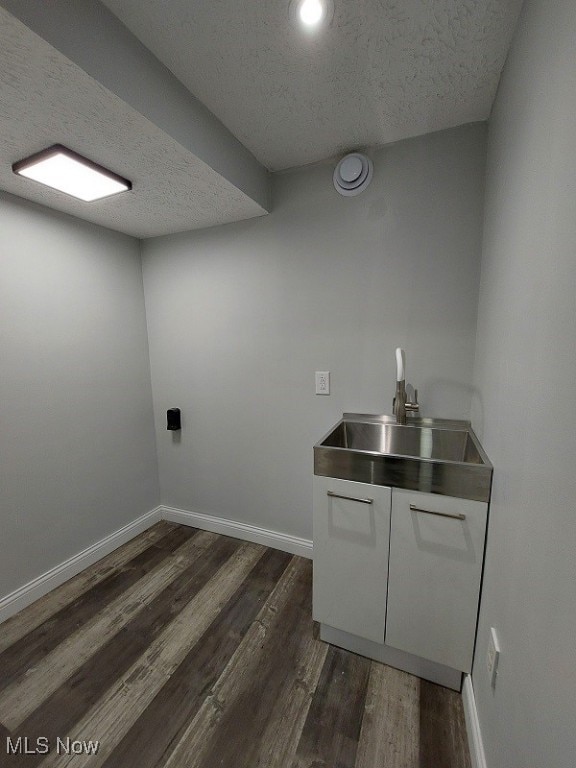 laundry area with dark hardwood / wood-style floors, sink, and a textured ceiling