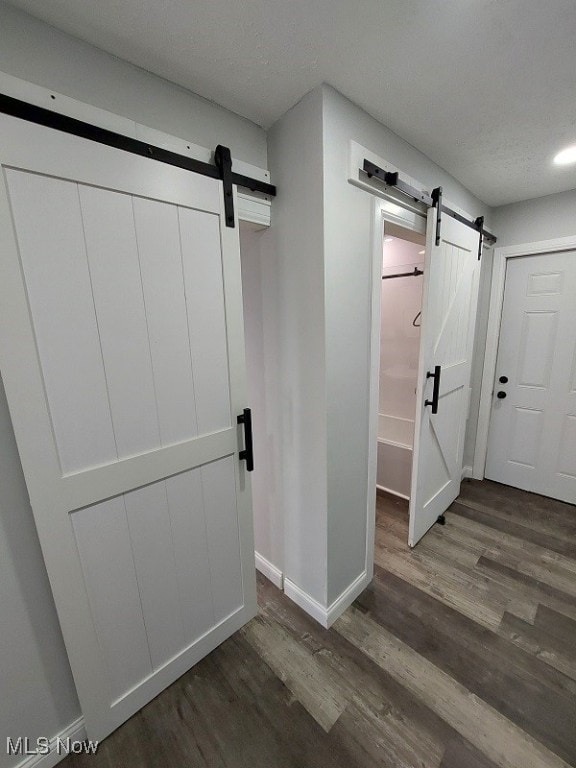 interior space featuring wood-type flooring, a textured ceiling, and a barn door