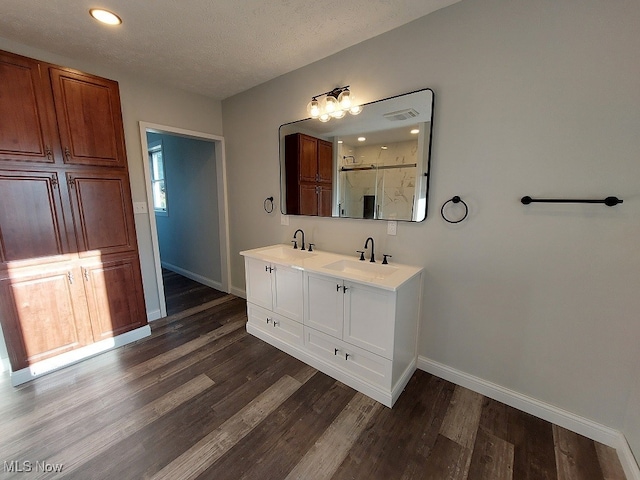 bathroom with an enclosed shower, hardwood / wood-style floors, vanity, and a textured ceiling