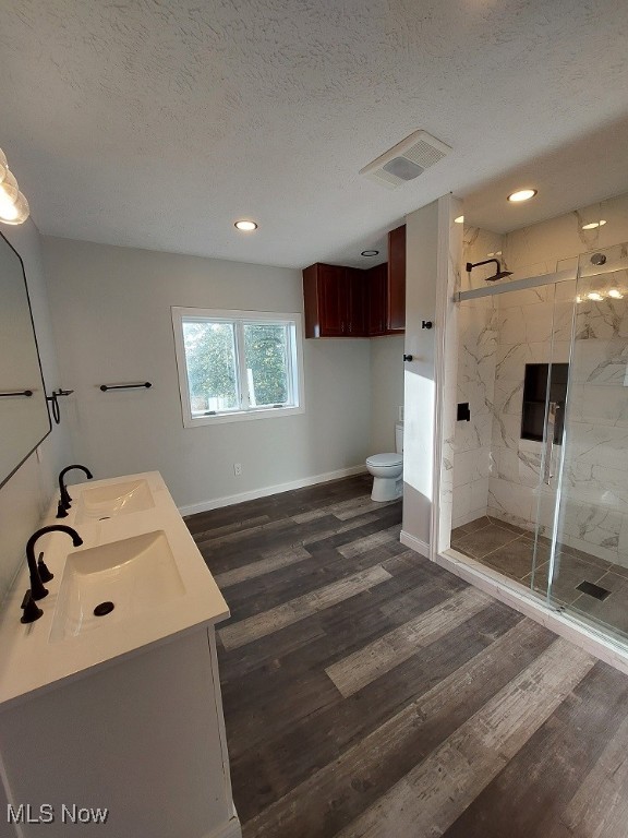 bathroom featuring hardwood / wood-style floors, a shower with shower door, vanity, and toilet