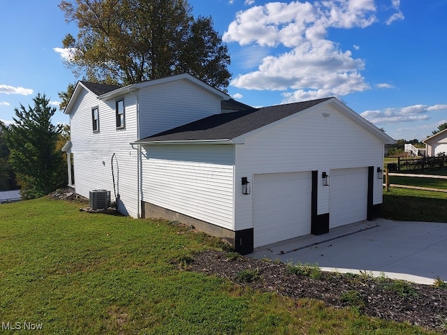 view of side of home with cooling unit, a lawn, and a garage