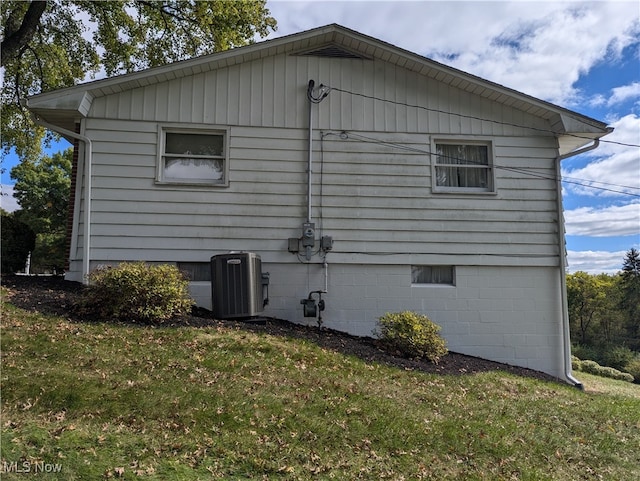 view of side of property with a yard and central air condition unit