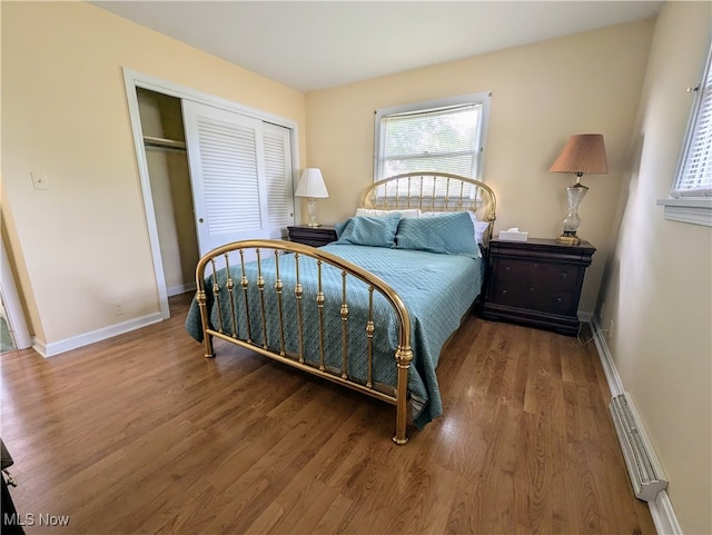 bedroom with wood-type flooring, a baseboard radiator, and a closet