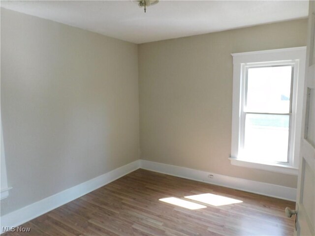 386 Jackson St, Conneaut, OH 44030 - empty room with wood finished floors, a healthy amount of sunlight, and baseboards