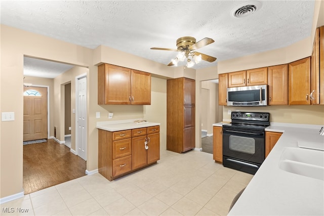 kitchen featuring black range with electric cooktop, light wood-type flooring, sink, and a textured ceiling