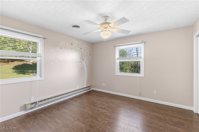 empty room featuring ceiling fan, dark wood-type flooring, a baseboard heating unit, and a textured ceiling