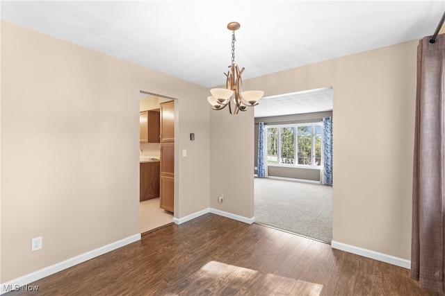 unfurnished dining area with a notable chandelier and dark wood-type flooring