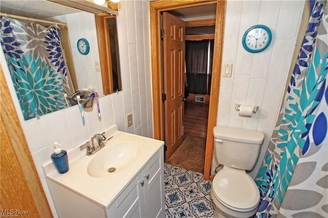 bathroom featuring vanity, walk in shower, tile walls, toilet, and a textured ceiling