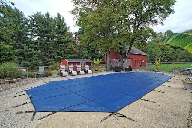 view of swimming pool with a patio and an outbuilding