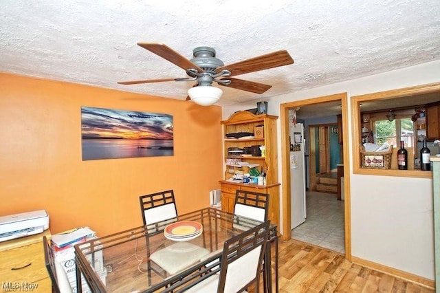 dining space with ceiling fan, a textured ceiling, and light wood-type flooring