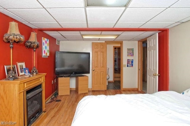 bedroom with a paneled ceiling and light wood-type flooring