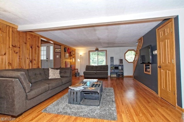 living room with wood walls, beamed ceiling, hardwood / wood-style floors, and a textured ceiling