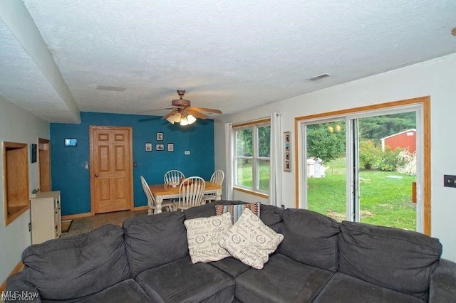 living room featuring ceiling fan and a textured ceiling