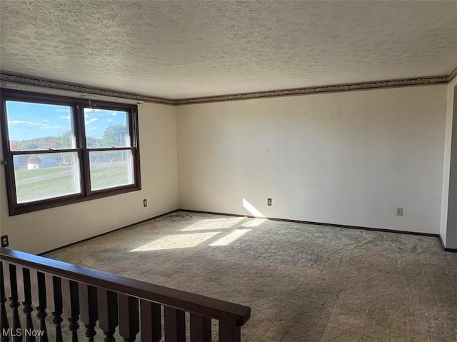 carpeted empty room featuring ornamental molding and a textured ceiling