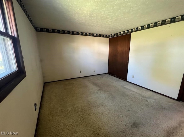 carpeted spare room with a textured ceiling