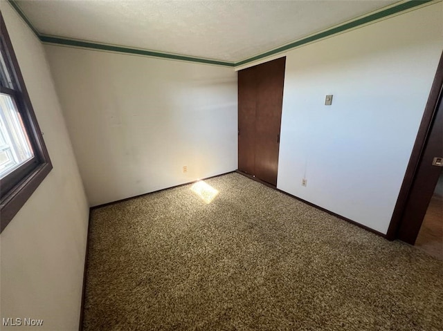 unfurnished bedroom with carpet floors, a textured ceiling, and ornamental molding