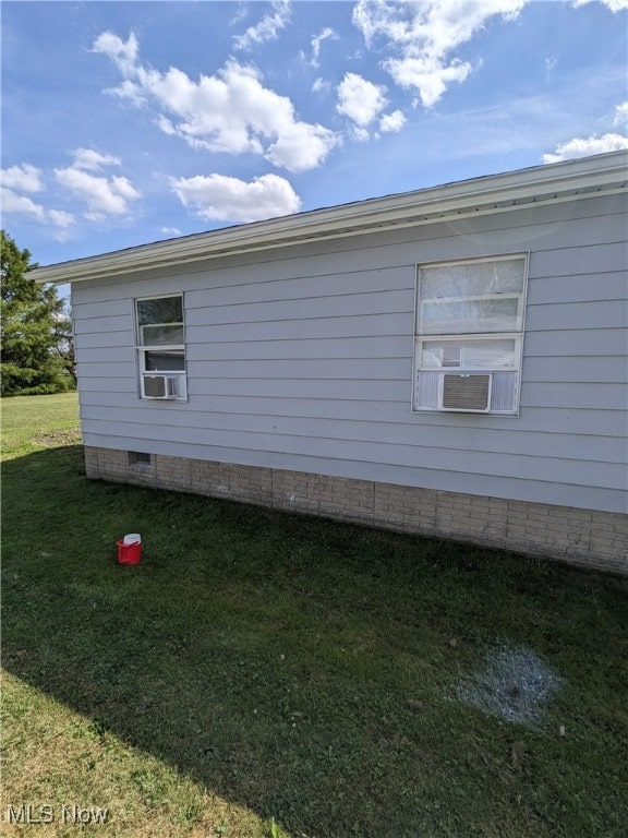 view of side of property featuring cooling unit and a yard