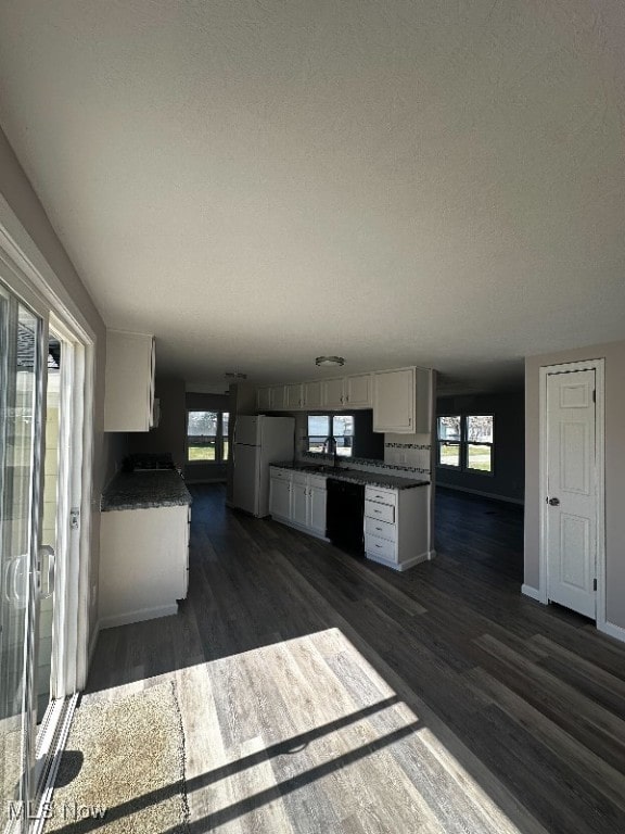 kitchen with white fridge, dark hardwood / wood-style flooring, a wealth of natural light, and white cabinets