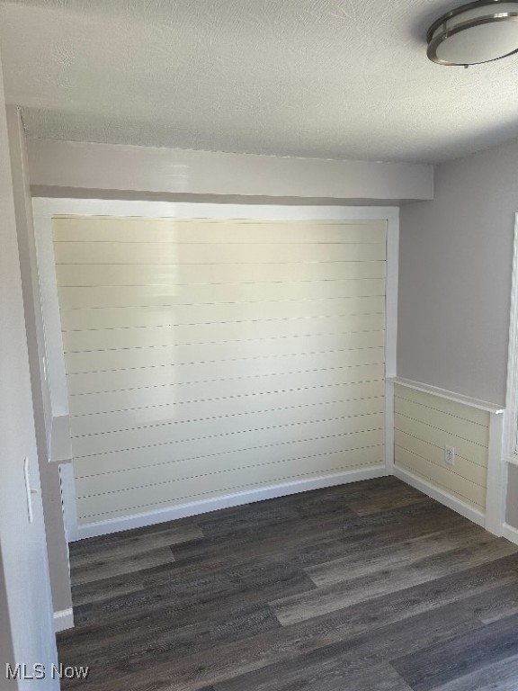 spare room featuring a textured ceiling and dark wood-type flooring