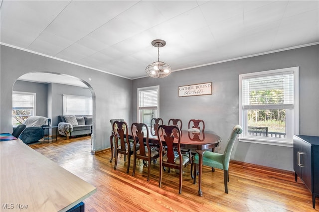 dining area with light wood-type flooring, ornamental molding, and a wealth of natural light