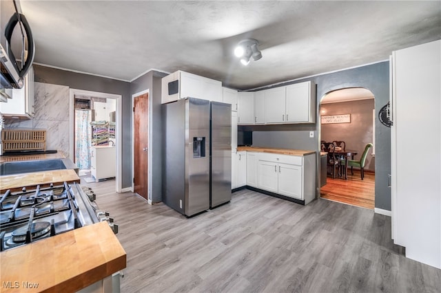 kitchen with appliances with stainless steel finishes, light hardwood / wood-style flooring, and white cabinets