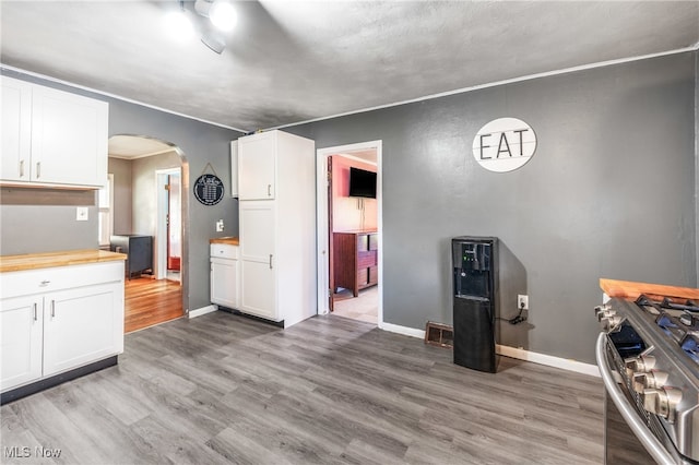 kitchen featuring butcher block countertops, gas stove, white cabinetry, and hardwood / wood-style floors