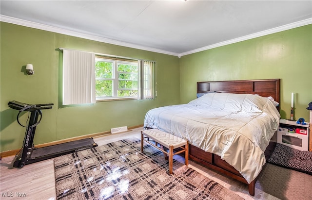 bedroom with crown molding and light wood-type flooring