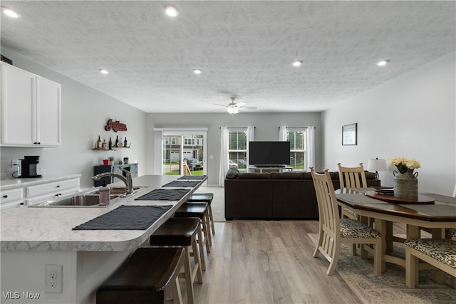 kitchen featuring white cabinetry, sink, light hardwood / wood-style floors, and a textured ceiling