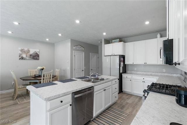 kitchen with light hardwood / wood-style flooring, appliances with stainless steel finishes, a kitchen island with sink, and white cabinetry