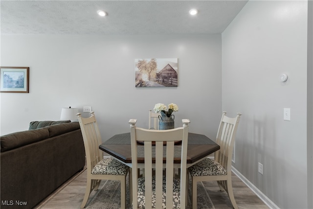 dining area with light hardwood / wood-style floors and a textured ceiling